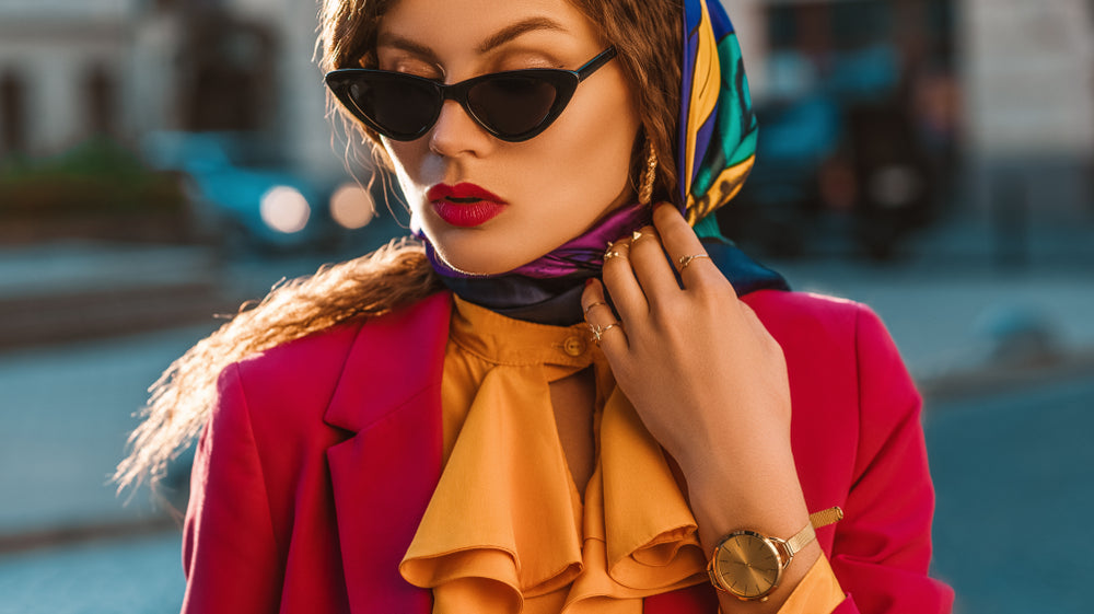 Fashionable woman in orange shirt with red blazer and colorful scarf around her head