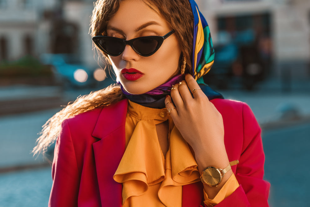 Fashionable woman in orange shirt with red blazer and colorful scarf around her head